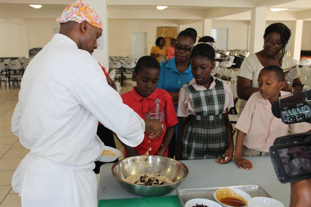 Students of the Charlestown Primary School look on at a Mini Chef Academy session as Celebrity Chef of Atlanta Marvin Woods demonstrates how to make healthy snacks at the school’s kitchen on February 24, 2015