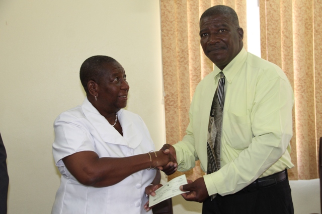 Dr. Robertine Chaderton, Chairman of the St. Kitts and Nevis Sugar Industry Diversification Foundation Board of Counsellors, presents a cheque to Edson Elliott, Principal of the Charlestown Secondary School and the Nevis Sixth Form College, at a ceremony at the Ministry of Finance conference room in Charlestown on February 17, 2017, to assist with hosting the Leeward Islands Debating Competition