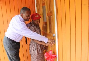 With a little help from Hon. Eric Evelyn, Minister responsible for Social Development on Nevis, new home owner Ms. Lorraine Cassandra Phillip opens the front door to her dwelling home at Fountain Village a gift from the ministry on June 14, 2018