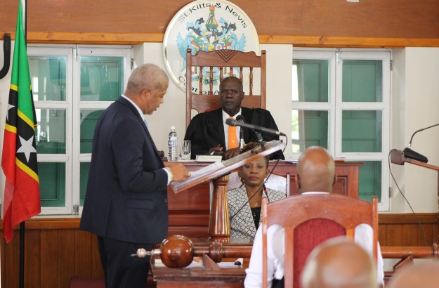 Hon. Spencer Brand, Minister of Physical Planning and Environment addressing a sitting of the Nevis Island Assembly at Hamilton House with Ms. Myra Williams, Clerk of the Assembly and Hon. Farrel Smithen, President of the Assembly looking on (file photo)