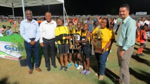 Athletes and staff of the Elizabeth Pemberton Primary School winners in Zone B of the 27th annual Gulf Insurance Inter-Primary Schools Championship with their trophy presented by (extreme right) Mr. Henry Francis Human Resource Manager of the Gulf Insurance Ltd. in Trinidad at the Nevis Athletic Stadium at Low Ground on April 03, 2019. Also present are (second from right) Hon. Eric Evelyn, Minister of Youth and Sports on Nevis, (second from left) Principal Ms. Shenelle Pemberton and (extreme left) another Gulf Insurance Representative