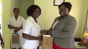 (L-r) Dahlia Simmonds, Community Health Nurse at the Brown Hill Health Centre, one of 116 nurses receiving a token of appreciation from Hon. Hazel Brandy-Williams, Junior Minister of Health on Nevis, on May 13, 2019, while Nurse Donna Hill, Community Health Nurse in charge of the centre looks on with her gift in hand
