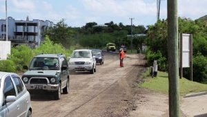 A flag lady operating near a corner of the road in Phase 1 of the Nevis Island Administration’s EC$6.7 million Island Main Road Rehabilitation and Safety Improvement Project from Cotton Ground to Cliff Dwellers