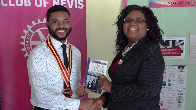 Mr. Kris Liburd, sitting President of the Rotaract Club of Nevis, presenting a gift of books to Ms. Zahnela Claxton, Principal Education Officer, on September 10, 2019 at the Department of Education