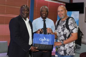 A representative from Cape Air presents a gift bag to Hon. Alexis Jeffers, Deputy Premier of Nevis (left) and Mr. Oral Brandy, General Manager of the Nevis Air and Sea Ports Authority (middle) at the Vance W. Amory International Airport VIP lounge on December 12, 2019, in celebration of the airline’s return to Nevis