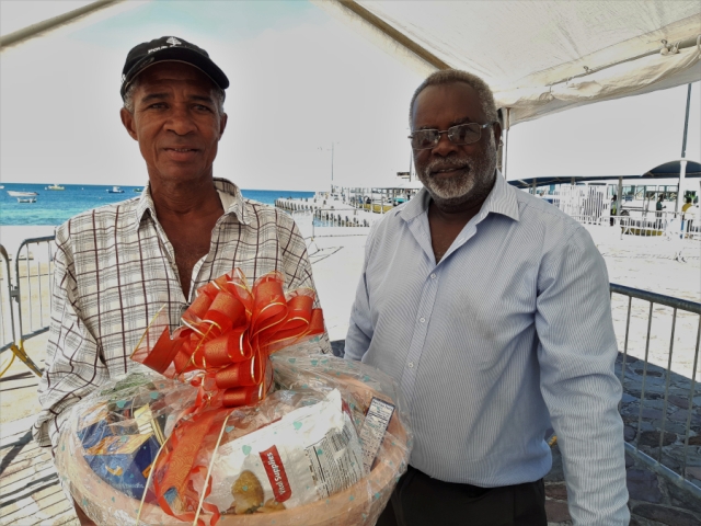 (L-r) Mr. Anthony Cranston, a sanitation worker at the Ministry of Health on Nevis being presented with a fruit basket by Mr. Ken Pembertion Manager of the Charlestown Port as a token of appreciation from the Nevis Air and Sea Ports Authority on Tuesday December 24th, 2019 at the Charlestown Pier