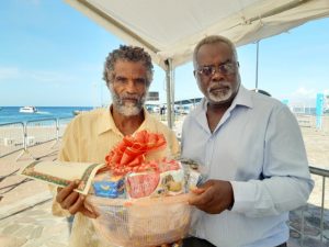 (L-r) Mr. Donald Browne, one of the sanitation workers at the Ministry of Health on Nevis being presented with a fruit basket by Mr. Ken Pembertion Manager of the Charlestown Port as a token of appreciation from the Nevis Air and Sea Ports Authority on Tuesday December 24th, 2019 at the Charlestown Pier