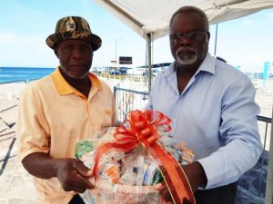 (L-r) Mr. Patrick Smithen, one of the sanitation workers at the Ministry of Health on Nevis being presented with a fruit basket by Mr. Ken Pembertion Manager of the Charlestown Port as a token of appreciation from the Nevis Air and Sea Ports Authority on Tuesday December 24th, 2019 at the Charlestown Pier