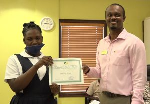 Adeille Webbe of the Charlestown Secondary School receiving the Bank of Nevis Limited’s Right Excellent Dr. Sir Simeon Daniel Scholarships for 2020 presented by Mr.Pheon Jones, Marketing Officer and Member of the Scholarship Committee on December 04, 2020