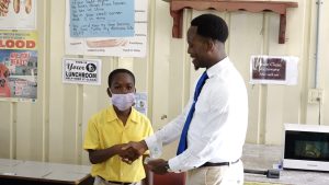 Mr. Mario Phillip, Gender Officer in the Department of Gender Affairs, presents an award to Cyprian David of the St. Thomas’ Primary School in observance of International Day of the Boy Child 2022